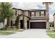 Two-story tan house with brown trim, stone accents, a dark brown garage door, and beautiful landscaping at 9221 Mountain Magnolia Dr, Riverview, FL 33578