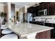 Close-up of kitchen island with granite countertops, stainless steel appliances, dark cabinets and tile backsplash at 9221 Mountain Magnolia Dr, Riverview, FL 33578