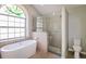 Luxurious bathroom with a soaking tub, glass-enclosed shower, and unique stained glass window at 4266 Candler Ave, Spring Hill, FL 34609