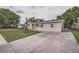 Side view of a single-story home featuring a concrete driveway, compact yard, and neutral exterior at 5429 Flora Ave, Holiday, FL 34690
