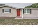 Close-up of the front exterior with a vibrant red door and tidy landscaping at 5429 Flora Ave, Holiday, FL 34690