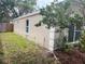 Beige home exterior with manicured landscaping, lawn, and white framed windows, nestled among green foliage at 12421 Early Run Ln, Riverview, FL 33578
