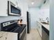 Well-equipped kitchen with stainless steel appliances, sleek white cabinetry, and marble countertops at 215 Medallion Blvd # G, Madeira Beach, FL 33708