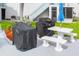 View of community patio area with grills, a white table, and benches under a blue umbrella at 215 Medallion Blvd # G, Madeira Beach, FL 33708