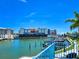 A waterfront view showing docked boats, a landscaped walkway, and nearby hotels on a sunny day at 215 Medallion Blvd # G, Madeira Beach, FL 33708