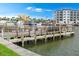 View of wooden dock on the waterfront, with buildings and boats visible in the background on a sunny day at 215 Medallion Blvd # G, Madeira Beach, FL 33708