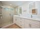 Spa-like bathroom showcasing dual vanities, a glass shower with tile surround, and modern light fixtures at 5108 Saint Albans Ave, Siesta Key, FL 34242
