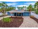 Charming blue single-story home featuring a covered front porch, brick driveway, and well-manicured landscaping at 5108 Saint Albans Ave, Siesta Key, FL 34242