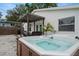 Backyard featuring a relaxing hot tub and cozy seating area under a shaded pergola at 135 Florida Blvd, Crystal Beach, FL 34681