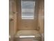 Standard bathroom with a shower-tub combo, window, and neutral tile at 1452 Crazy Horse Dr, Lutz, FL 33559