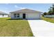 Charming single-story home with well-maintained lawn and two-car garage on a sunny day at 23461 Wickens Ave, Port Charlotte, FL 33980