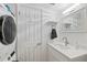 Bright, all white bathroom vanity with mirror, towel rack and stacked washer and dryer at 6210 Sun Blvd # 206, St Petersburg, FL 33715