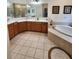 This bathroom features wood cabinets, a tile floor, and a soaking tub at 1829 Mira Lago Cir, Ruskin, FL 33570