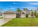 Charming single-story home with a well-maintained lawn, a two car garage and lovely landscaping with palm trees at 14256 Salvatierra Ln, Port Charlotte, FL 33981