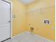 Laundry room with yellow walls, tile floors, and connections for a washer and dryer at 14256 Salvatierra Ln, Port Charlotte, FL 33981