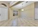 An empty living room featuring neutral tile flooring, natural light from a window, and a view to the front door at 14256 Salvatierra Ln, Port Charlotte, FL 33981