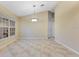 A neutral tiled floor living room with a modern light fixture and natural light entering through an exterior window at 14256 Salvatierra Ln, Port Charlotte, FL 33981