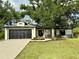 Charming single-story home featuring a black garage door, well-maintained lawn, and mature landscaping at 19543 Midway Blvd, Port Charlotte, FL 33948