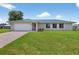 Charming single-story home featuring a green metal roof, brick driveway, and well-manicured lawn at 24277 Treasure Island Blvd, Punta Gorda, FL 33955