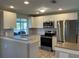 Bright kitchen with stainless steel appliances, tile backsplash, and a pass-through to the living area at 24277 Treasure Island Blvd, Punta Gorda, FL 33955