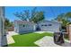 Landscaped backyard with artificial turf, stone pavers, and a detached garage; great for entertaining at 6020 Illinois Ave, New Port Richey, FL 34653