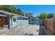 Blue house exterior featuring a concrete patio, privacy fence, and a back door at 6020 Illinois Ave, New Port Richey, FL 34653