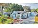 Charming blue home featuring a well-manicured lawn, mature trees, and a welcoming front porch at 6020 Illinois Ave, New Port Richey, FL 34653