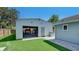 Detached garage with roll up door and space for parking, adjacent to artificial grass yard and paving at 6020 Illinois Ave, New Port Richey, FL 34653