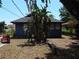 Backyard view of a cozy blue home with mature trees and a rustic fire pit at 834 Jackson N St, St Petersburg, FL 33705