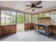 Enclosed screened porch featuring a ceiling fan, views of the yard, and an area for storage or workspace at 20703 Old Trilby Rd, Dade City, FL 33523