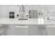 Close-up of white kitchen island with quartz countertop and barstool seating, featuring stainless steel appliances at 28761 Sweet Persimmon Dr, Wesley Chapel, FL 33543