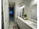 Bright bathroom featuring double sinks with white cabinets and a view of an open doorway at 10153 Wildcat St, Port Charlotte, FL 33981