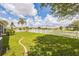 Expansive backyard with a lush green lawn, white picket fence, and scenic lake view at 6935 Runner Oak Dr, Wesley Chapel, FL 33545