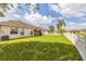 Large backyard with lush green grass, white picket fence, and distant view of neighboring homes at 6935 Runner Oak Dr, Wesley Chapel, FL 33545