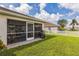 Backyard featuring a well-manicured lawn, screened-in patio, and white picket fence at 6935 Runner Oak Dr, Wesley Chapel, FL 33545