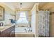 Bright bathroom featuring a soaking tub with bronze fixtures and decorative shower curtain at 6935 Runner Oak Dr, Wesley Chapel, FL 33545