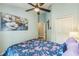 Bright bedroom with a floral bedspread, ceiling fan, and decorative floral artwork at 6935 Runner Oak Dr, Wesley Chapel, FL 33545