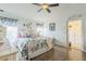 Bright bedroom featuring wood floors, a ceiling fan, and a comfortable floral-themed bed at 6935 Runner Oak Dr, Wesley Chapel, FL 33545