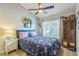 Comfortable bedroom with a ceiling fan, light walls, floral bedspread, and decorative cabinet at 6935 Runner Oak Dr, Wesley Chapel, FL 33545
