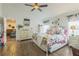 Bright bedroom featuring wood floors, a ceiling fan, and a comfortable floral-themed bed at 6935 Runner Oak Dr, Wesley Chapel, FL 33545