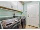 Laundry room with modern machines, overhead cabinets and a convenient side access door at 6935 Runner Oak Dr, Wesley Chapel, FL 33545