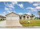 Beautiful single-story home with a two-car garage, lush lawn, and a welcoming arched entryway with decorative windows at 924 Texas St, Englewood, FL 34223