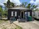 View of the home's front exterior featuring a concrete porch, black textured walls, and two shuttered windows at 3613 Deleuil Ave, Tampa, FL 33610