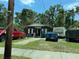 Street view showcasing the home's exterior and front yard with parked vehicles and overgrown grass at 3613 Deleuil Ave, Tampa, FL 33610