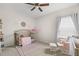 Light and airy bedroom with a crib, rocking chair, a rug and a window with curtains at 7163 Talamore Dr, Wesley Chapel, FL 33545
