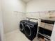 Laundry room with dark blue washer and dryer, shelving, and tiled floor at 7163 Talamore Dr, Wesley Chapel, FL 33545