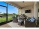 Covered patio area with wicker furniture, grill, television, and view of the pond at 7163 Talamore Dr, Wesley Chapel, FL 33545