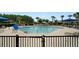 Community pool with lounge chairs and umbrellas behind a black metal fence at 7163 Talamore Dr, Wesley Chapel, FL 33545