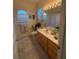 Bright bathroom features a marble vanity, arched windows, and a tub with shower at 10937 Bluestem Cir, Lakewood Ranch, FL 34202