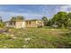 Exterior shot of the yellow home showcasing the spacious backyard and mature trees on a sunny day at 5101 Town N Country Blvd, Tampa, FL 33615